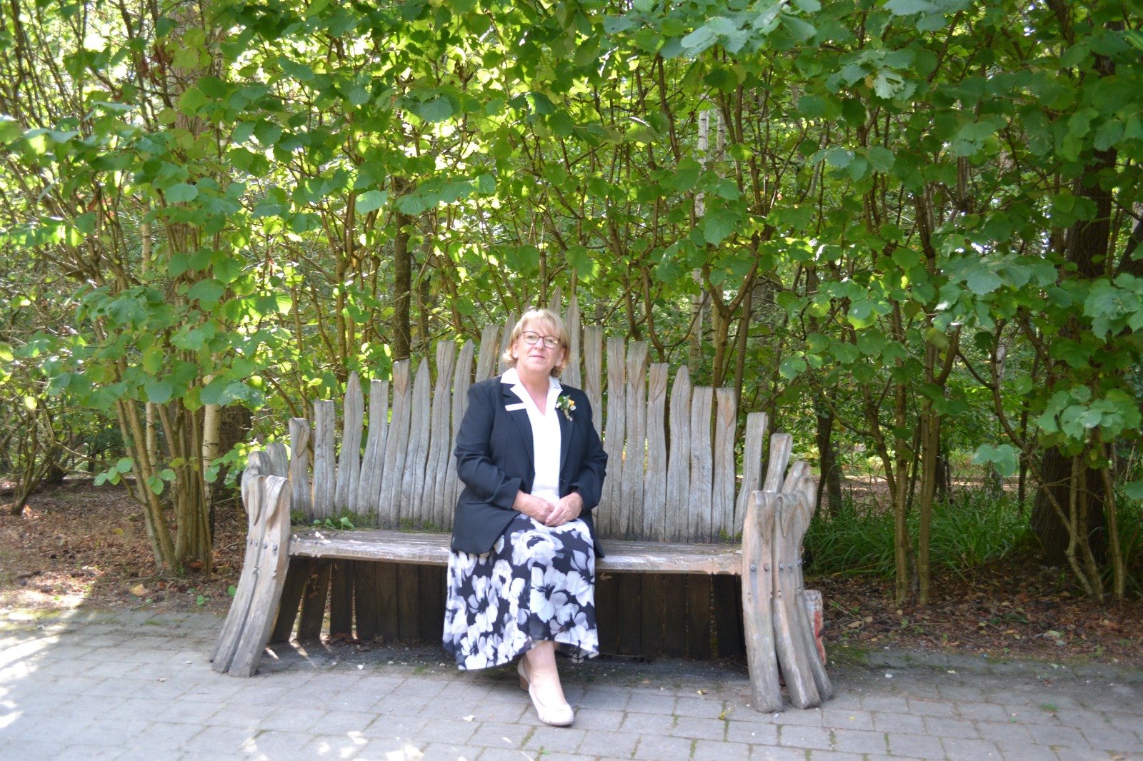 Caroline seated on a carved wooden bench in a woodland